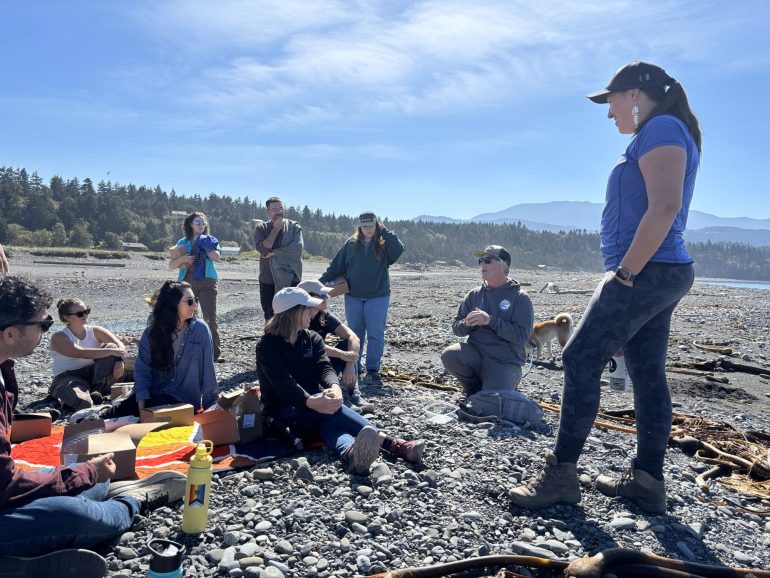 A group of fellows sitting on a beach on a sunny day
