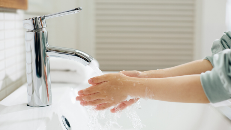 A child washing their hands at a sink