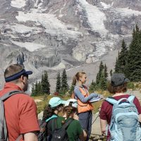 Several hikers in the foreground with a large mountain in the background