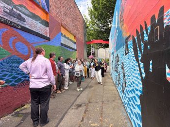 Group of people on a tour looking at colorful wall murals in an alley